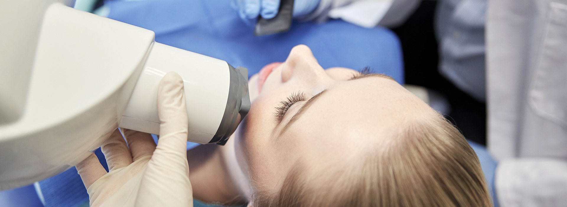 A woman receiving a dental implant procedure, with the dentist using a microscope to guide the implant placement.