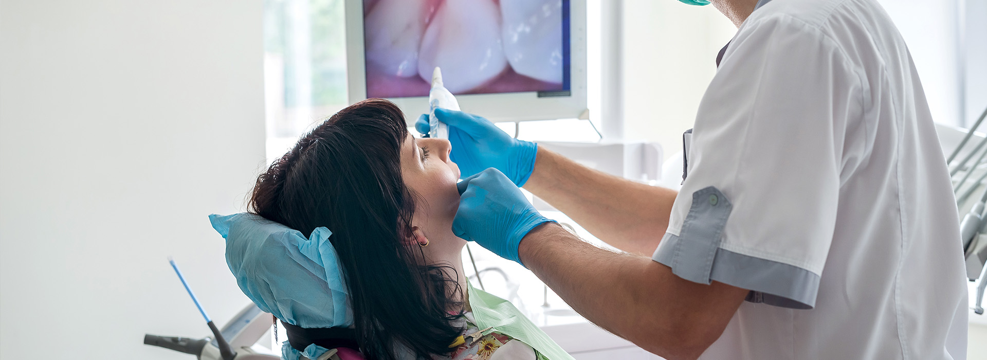 In the image, a dental hygienist is performing a cleaning procedure on a patient s teeth in an office setting.