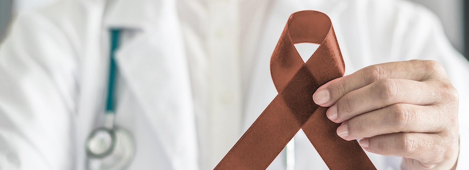 The image shows a healthcare professional holding a red ribbon with the AIDS symbol, which is commonly associated with HIV awareness.