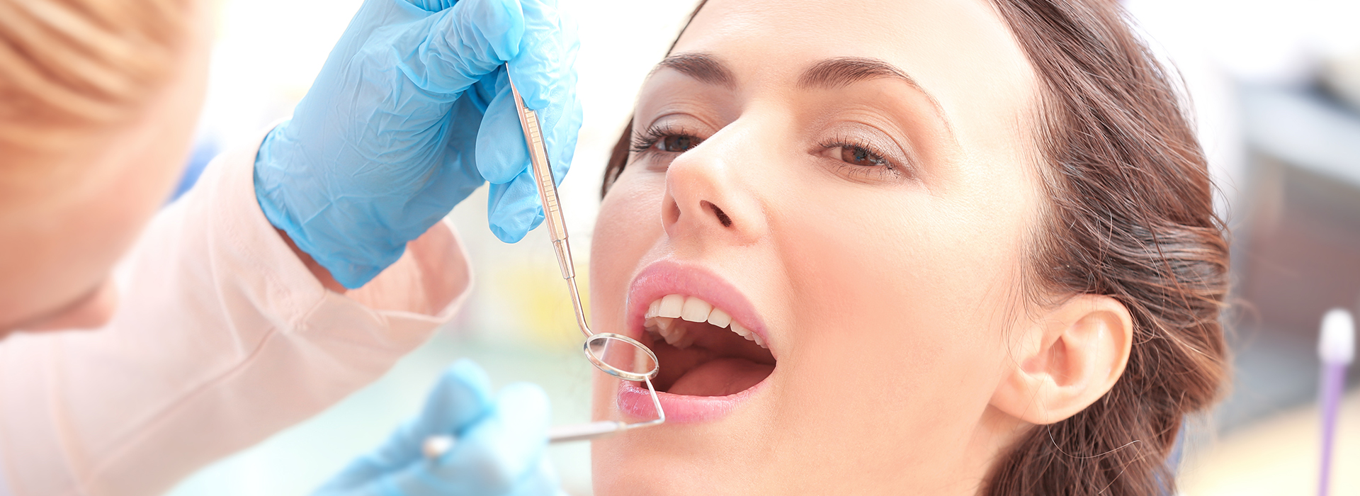 Woman receiving dental implant procedure with dentist and assistant in medical setting.