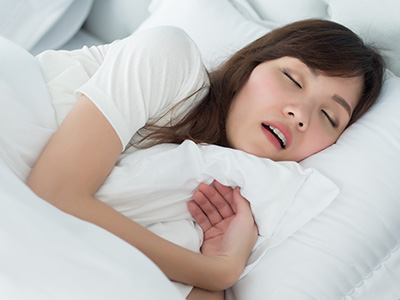 The image shows a person lying in bed with their eyes closed, appearing to be asleep or resting.